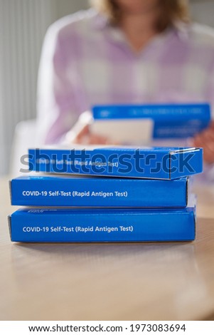 Close Up Of Woman At Home Reading Instructions On Supply Of Covid-19 Rapid Antigen Self-Testing Kits  Royalty-Free Stock Photo #1973083694