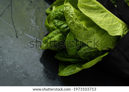 close-up of a reusable black grocery bag with salad on a black background