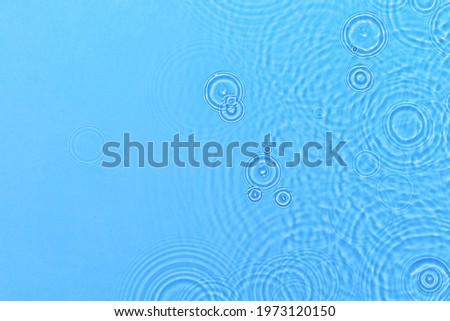De-focused transparent blue colored clear calm water surface texture with ripples, splashes and bubbles. Trendy abstract nature background. Water waves in sunlight with copy space.