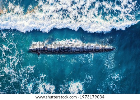 Combat military nuclear diesel electric submarine on background of blue ocean water. Top view aerial drone. Royalty-Free Stock Photo #1973179034