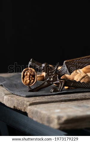 Dragon nutcracker is holding unshelled walnut on rustic napkin and wooden table. vertical