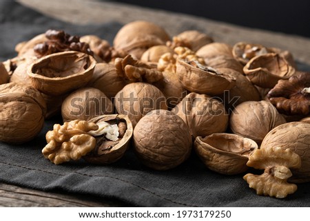Tasty walnuts with cracked split nutshells on rustic napkin and wood table Royalty-Free Stock Photo #1973179250