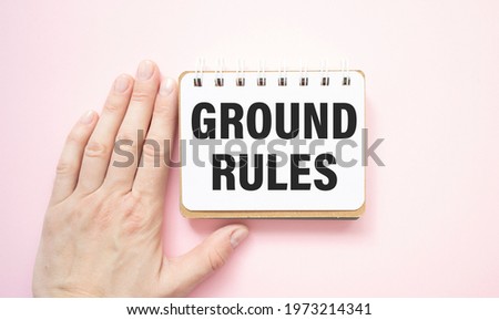 Closeup on businessman holding a card with text GROUND RULES, business concept image with soft focus background and vintage tone