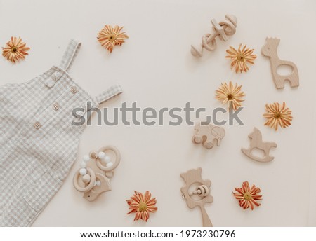 Light soft baby pants with wooden toys and flowers. Fashion newborn, bohemian style, neutral beige colors. Flat lay, top view. Natural textile, pastel background. 
