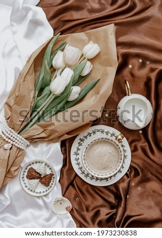 White tulips  and coffee cup on silky background. Elegant morning, breakfast for woman, valentine day woman day 