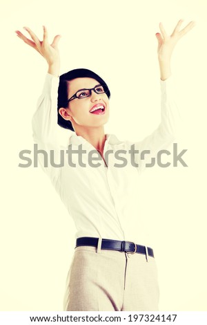 Smiling young woman is holding something abstract above her head. Happy girl with raised hands.