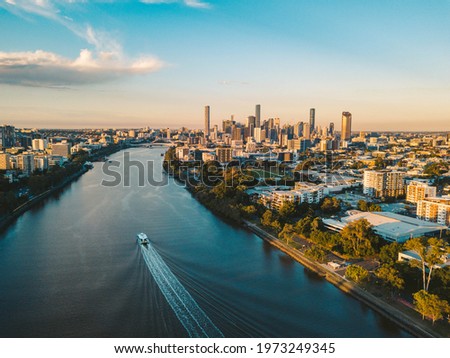 Sunset aerial shot of Brisbane as a City Cat heads towards the city on the Brisbane River