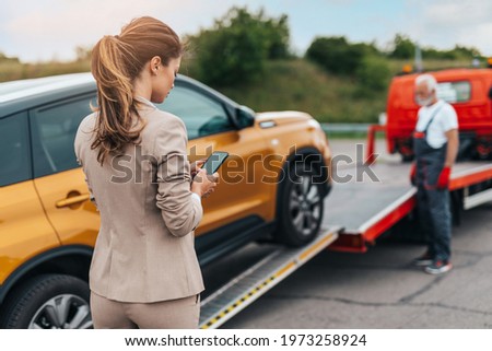 Elegant middle age business woman calling someone while towing service helping her on the road. Roadside assistance concept.	 Royalty-Free Stock Photo #1973258924