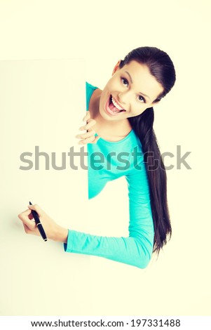 Happy beautiful woman writing with a pen on blank board. Student or businesswoman.