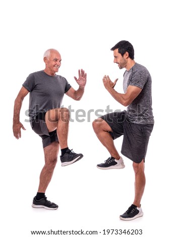 Elderly male client exercising with a fitness trainer, exercise walking in place, steps. On a white isolated background. Royalty-Free Stock Photo #1973346203