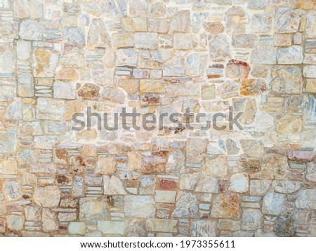 Masonry concept. Old weathered exterior rough strong stonewall background texture. Cobblestone, floor beige brown grey empty for backdrop. Rocks connected with cement solid construction. Border fence. Royalty-Free Stock Photo #1973355611