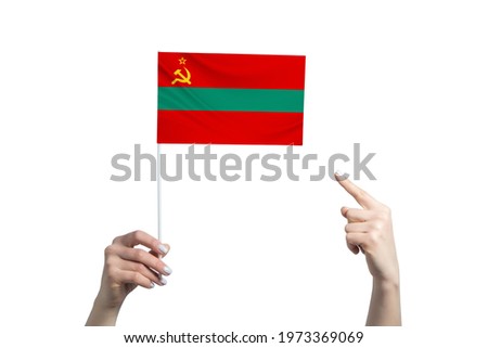 A beautiful female hand holds a Transnistria flag to which she shows the finger of her other hand, isolated on white background.