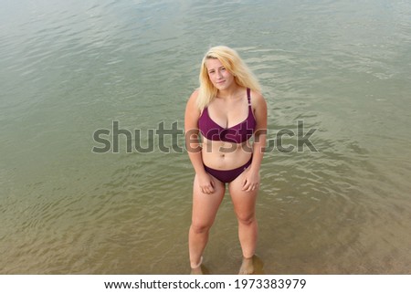 A young girl in a swimsuit stands in the water. View from above.