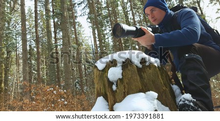 photographer. young man with tele photo camera in forest. nature shot