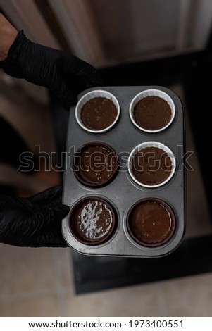 Women's hands put a tray of cakes in the oven to bake them