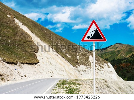 International traffic sign 'Falling rock' standing on highway road. North Caucasus, Republic of Ingushetia, Russia 