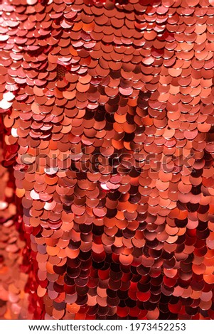 red shiny sequins close-up. vertical shiny background. red glitter scales