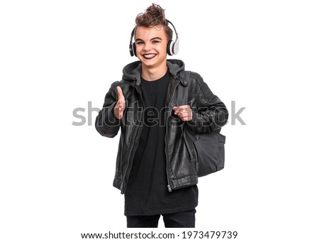 Portrait of teen boy student in headphones with spooking make-up holds bag, isolated on white background. Teenager with backpack in style of punk goth dressed in black. Problems of transitional age