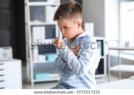 Ill coughing little boy visiting doctor in clinic Royalty-Free Stock Photo #1973517233