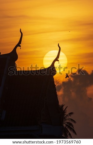 Silhouette of Sunrise at the roof of thai architecture temple and the flying bird. minimal style.