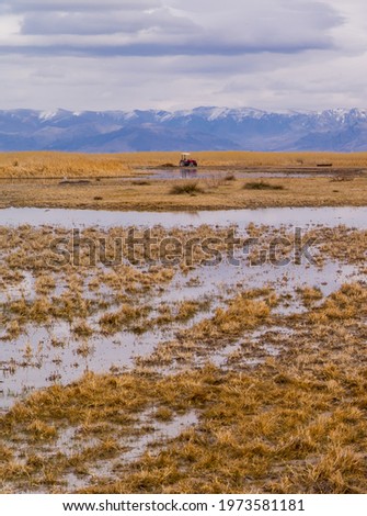 Vertical view of a tractor in front of a lake and marshes in Sultan Reedy (Sultansazligi) National Park, central Turkey on a cloudy day
