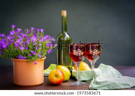 Antique stylized still life with a bouquet of roses, a bottle of wine and apples.