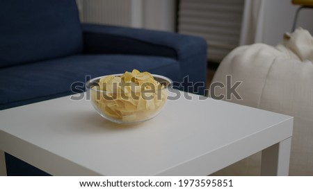 Closeup of junk fried potato bowl put on woden table in empty party room with nobody in it. Apartament is ready for friends gathering celebrating wekeend birthday party late at night