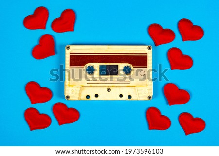 Old Audio Cassette with a Red Hearts on the Blue Paper Background closeup