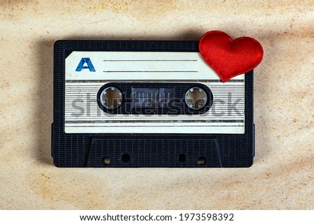 Old Audio Cassette with a Red Heart on the Old Paper Background closeup