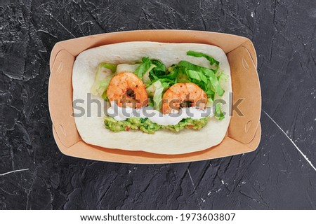 shrimp tacos in a craft container on an isolated dark background. Take away food. Photo for menu and site. Close up