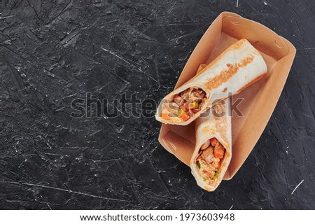 mexican burritos in a craft container on an isolated dark background. Take away food. Photo for menu and site. Close up