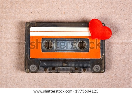 Old Audio Cassette with a Red Heart on the Cardboard Background closeup