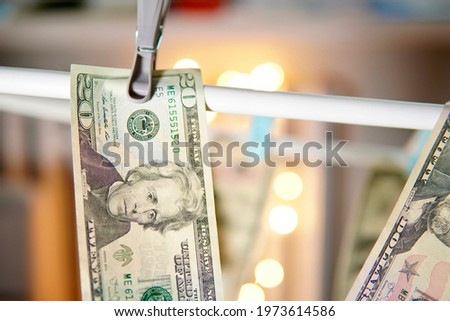 conceptual photo showing money laundering. dollars of various denominations hang pinned with clasps. Money from criminal activity.