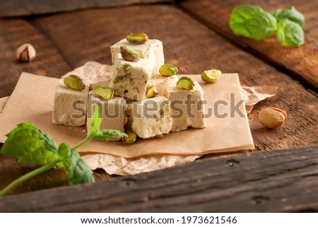Walnut halva with pistachios on parchment paper on a wooden background. Traditional oriental dessert Chekme. Natural vegan product. Turkish, Arab and Jewish national sweets