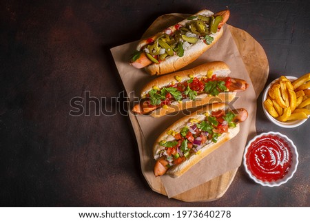 Hot dogs with different spicy toppings, dark background with copy space, horizontal Royalty-Free Stock Photo #1973640278