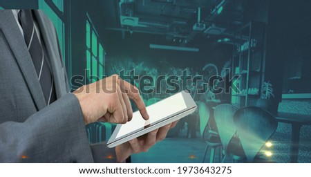 Composition of midsection of businessman using tablet over green interiors. global business and technology concept digitally generated image.