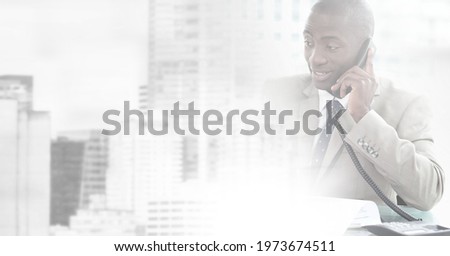 Composition of cityscape over african american businessman using phone. global business, finance and networking concept digitally generated image.