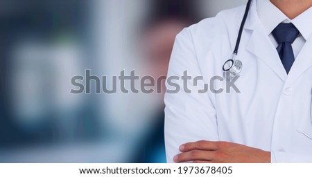 Composition of midsection of male doctor in lab coat with stethoscope over out of focus hospital. medicine and science concept digitally generated image.