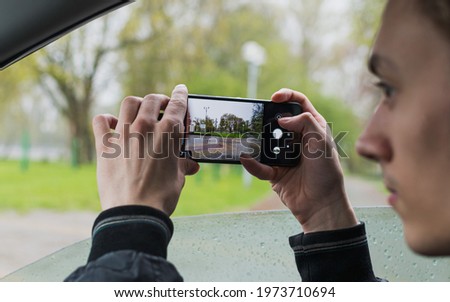 A young guy takes pictures of the city landscape from the car window