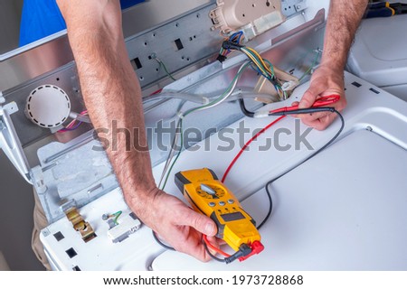 Hands of an appliance technician troubleshooting or repairing a washing machine Royalty-Free Stock Photo #1973728868
