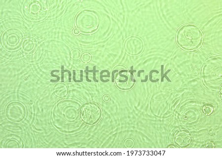 De-focused closeup of mint green transparent clear water surface texture with ripples, splashes and bubbles. Trendy abstract summer nature background. Mint colored waves in sunlight with copy space.