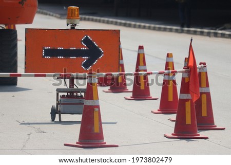 Under construction sign with arrow sign and traffic cone. 