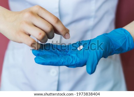 The doctor's hand, a nurse in a blue latex glove gives a pill in the palm of a sick patient. A blurry hand takes the medicine. The concept of medical care, speedy recovery