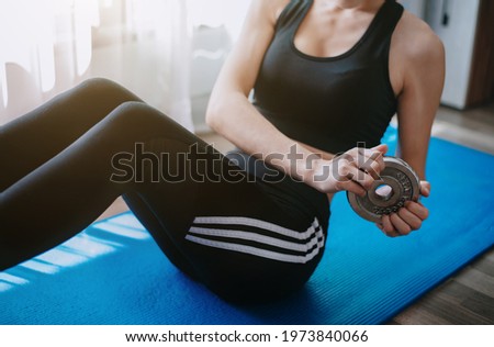Coronavirus, women doing abdomen exercise on the floor. women doing workout using a dumbbell at the home Instead of going to the gym.