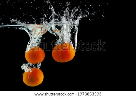 three fresh tangerines fell into the water with splashes