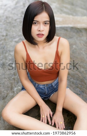 A woman short hairs in short pants and waistcoat on nature water and waterfall , she enjoy and relax time in weekends 