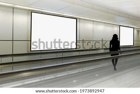 Mockup visual for advertising billboard display: person walking on moving walkway travelator in generic mrt train station. Blank billboards advertising space for mock up purpose; OOH ad placement Royalty-Free Stock Photo #1973892947