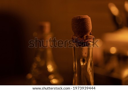 Wooden cork in glass thin neck of bottle with balsamic vinegar, oil, sauce, in an italian cuisine, cafe, restaurant, warm blurred background. Close-up, macro