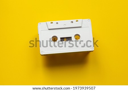 blank audio cassette hovering over yellow background