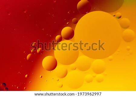 Macro photography of the oil drops on the water surface.Vibrant red and orange gradient.Cosmic circles looks like molecule structure.Backdrop with copy space,good as template.